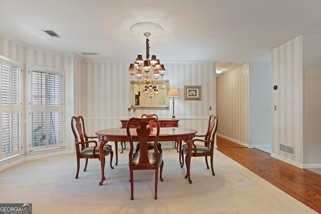 dining room featuring a notable chandelier, ornamental molding, and light hardwood / wood-style flooring