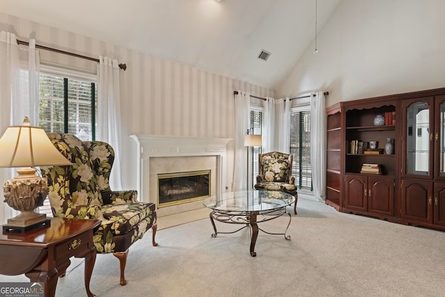 sitting room featuring light carpet, a high end fireplace, and a wealth of natural light