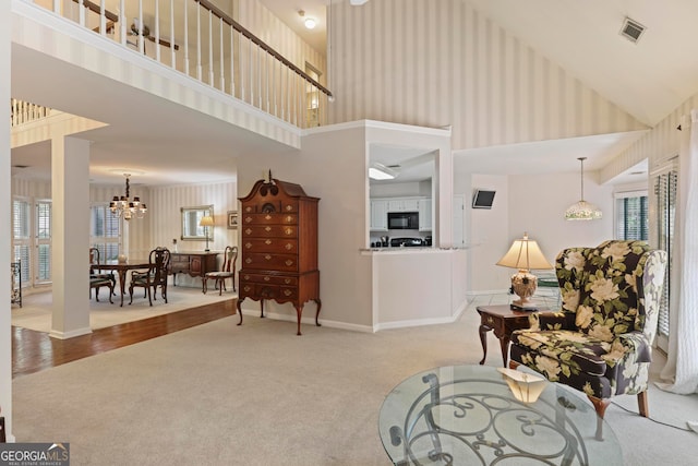 living area with high vaulted ceiling, an inviting chandelier, and light colored carpet