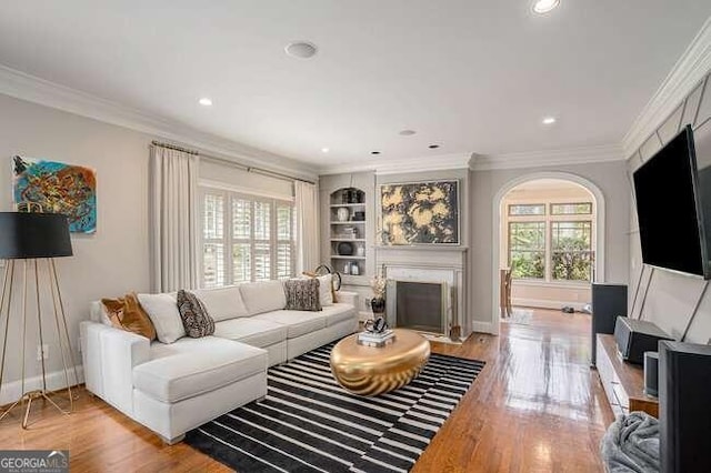 living room featuring built in shelves, light hardwood / wood-style floors, and ornamental molding