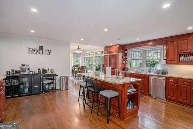 kitchen featuring stainless steel dishwasher, a kitchen breakfast bar, a center island, and hardwood / wood-style floors