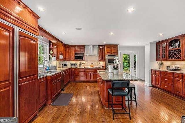 kitchen featuring hardwood / wood-style floors, wall chimney exhaust hood, a center island, and stainless steel appliances