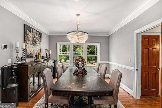 dining area featuring wood-type flooring, a notable chandelier, and ornamental molding