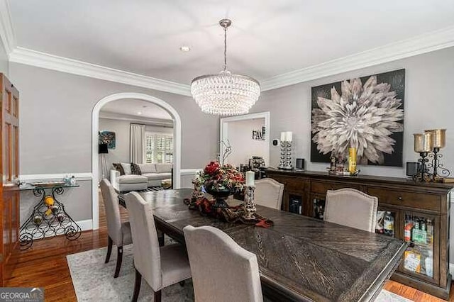 dining room featuring dark hardwood / wood-style flooring, ornamental molding, and a chandelier