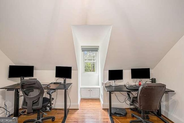 home office with light wood-type flooring and vaulted ceiling