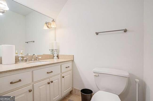 bathroom featuring tile patterned flooring, vanity, toilet, and lofted ceiling