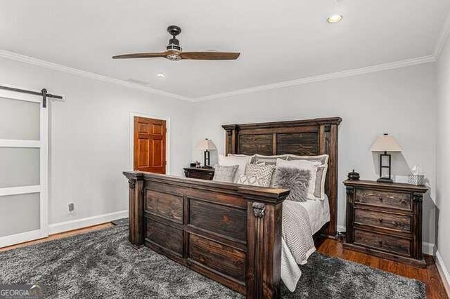 bedroom featuring a barn door, ceiling fan, crown molding, and dark hardwood / wood-style flooring