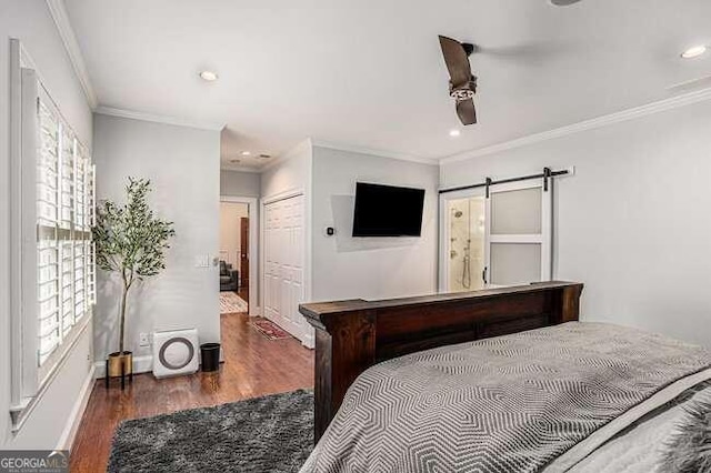 bedroom with ceiling fan, dark wood-type flooring, a barn door, crown molding, and ensuite bathroom