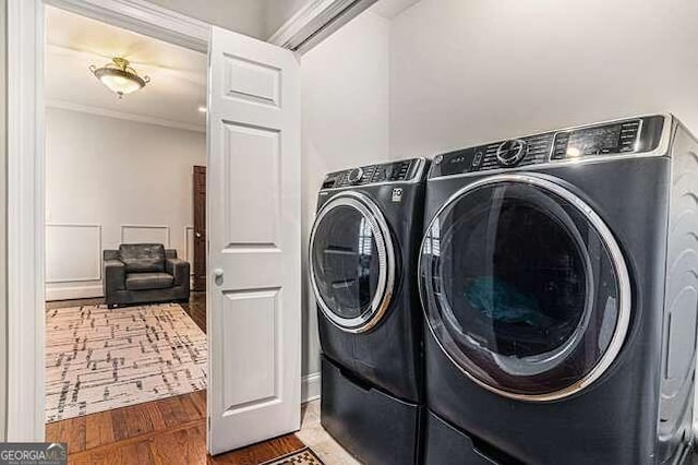 washroom featuring washer and dryer, dark hardwood / wood-style flooring, and crown molding