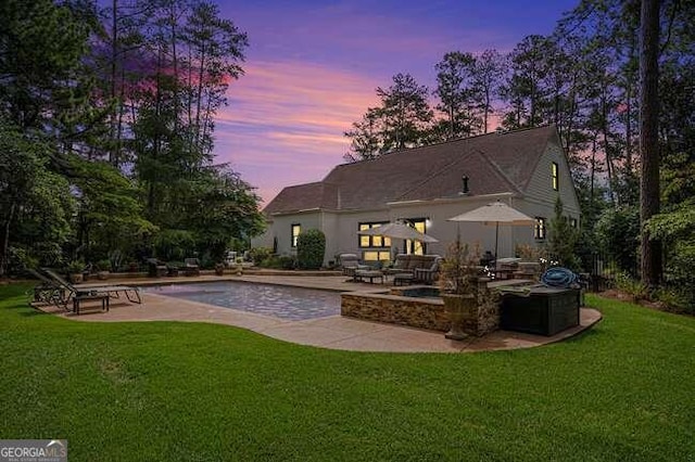 pool at dusk with a yard and a patio