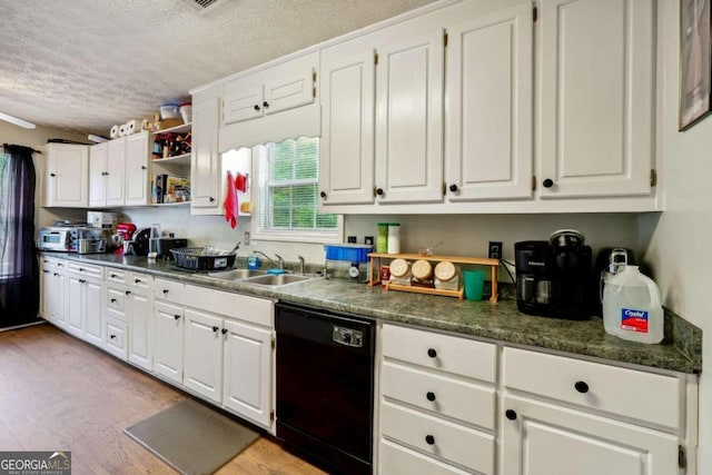 kitchen with dishwasher, dark countertops, light wood-style floors, white cabinetry, and a sink