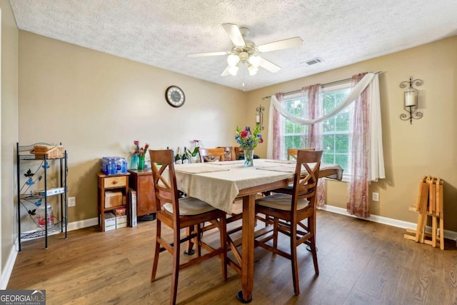 dining room with visible vents, wood finished floors, a ceiling fan, and baseboards