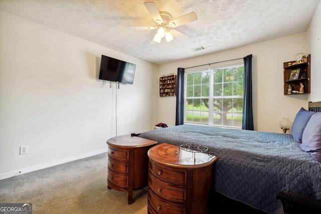 carpeted bedroom with a textured ceiling, a ceiling fan, visible vents, and baseboards