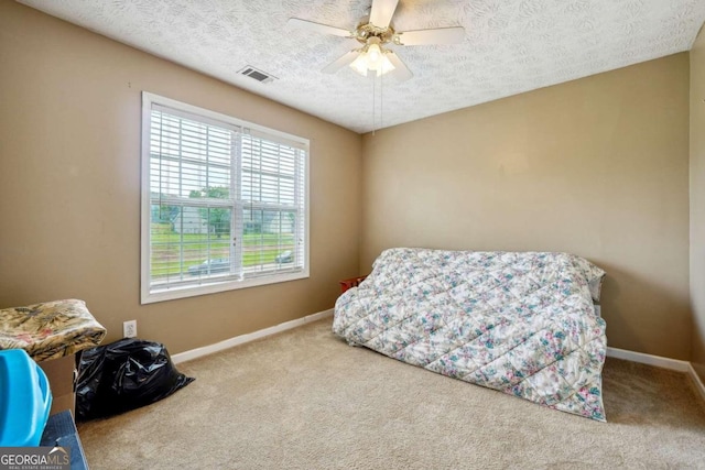 carpeted bedroom with a textured ceiling, ceiling fan, visible vents, and baseboards