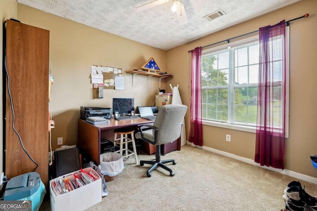 carpeted home office featuring visible vents, ceiling fan, a textured ceiling, and baseboards