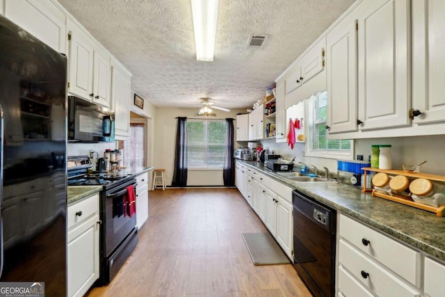 kitchen with black appliances, dark countertops, and white cabinets