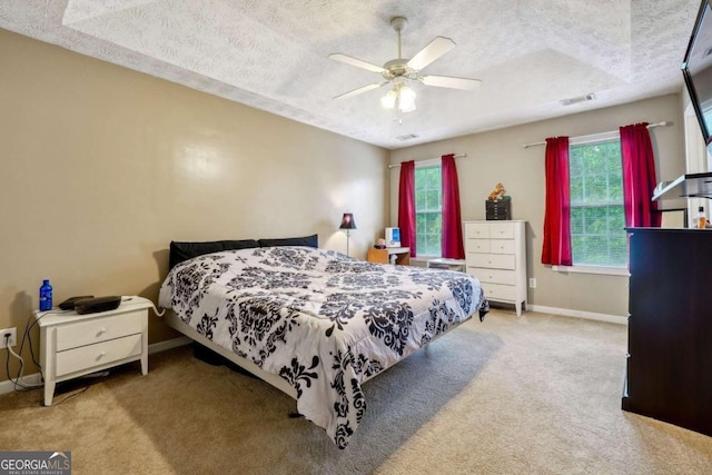 bedroom featuring light carpet, visible vents, baseboards, and a textured ceiling