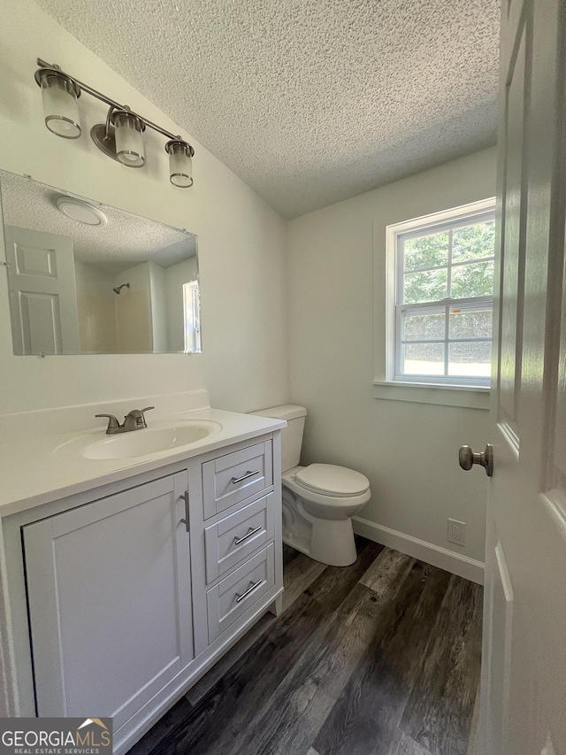 bathroom featuring lofted ceiling, hardwood / wood-style flooring, vanity, a textured ceiling, and toilet