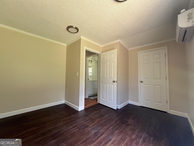 unfurnished bedroom featuring ornamental molding, dark hardwood / wood-style floors, a wall mounted air conditioner, and a textured ceiling