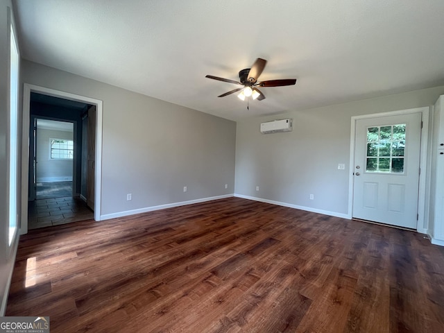 empty room featuring dark wood-type flooring, ceiling fan, and an AC wall unit