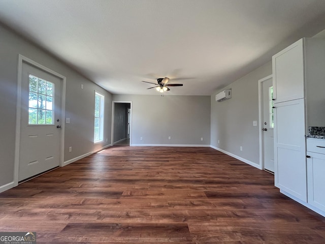 interior space featuring dark wood-type flooring, an AC wall unit, and ceiling fan