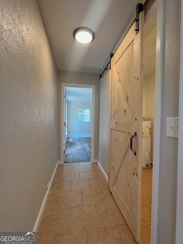 hall featuring a barn door, electric water heater, and light tile patterned floors