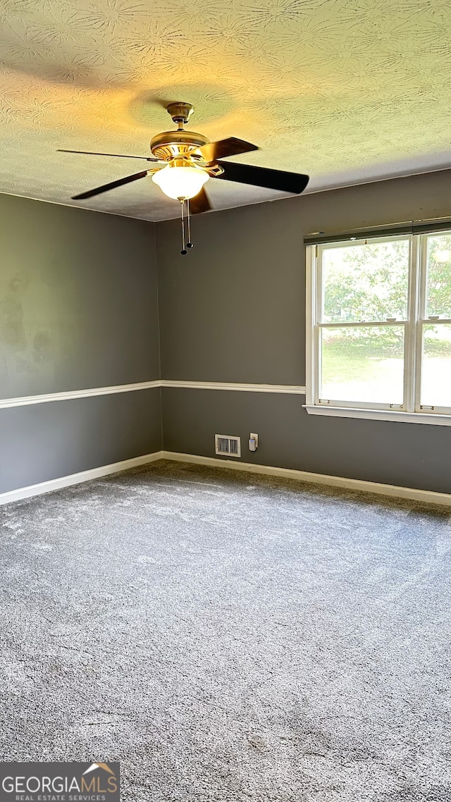 carpeted spare room with a textured ceiling, a wealth of natural light, and ceiling fan