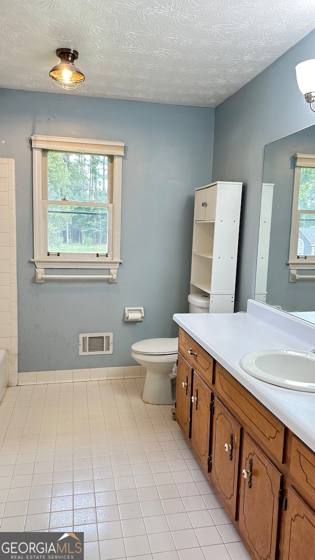 bathroom with tile patterned floors, toilet, a textured ceiling, and vanity