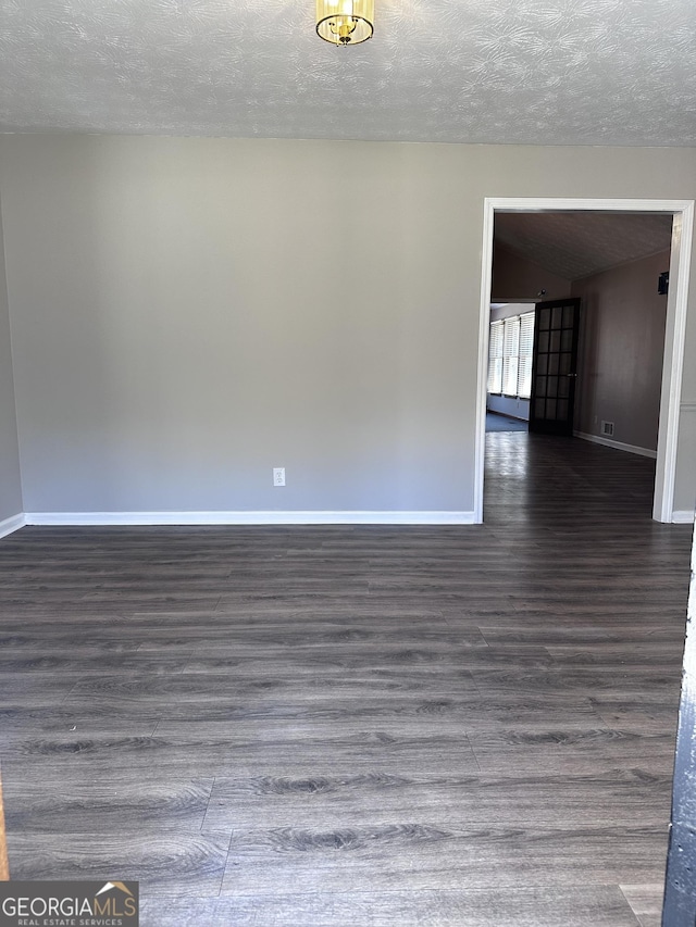 empty room with a textured ceiling, wood finished floors, and baseboards