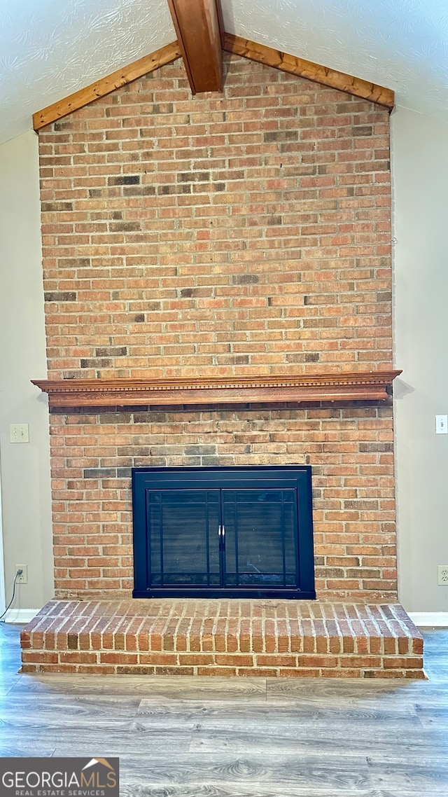 interior details featuring hardwood / wood-style flooring, a textured ceiling, and a brick fireplace