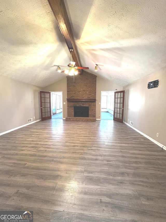 unfurnished living room featuring dark wood-style floors, a fireplace, lofted ceiling with beams, and a textured ceiling