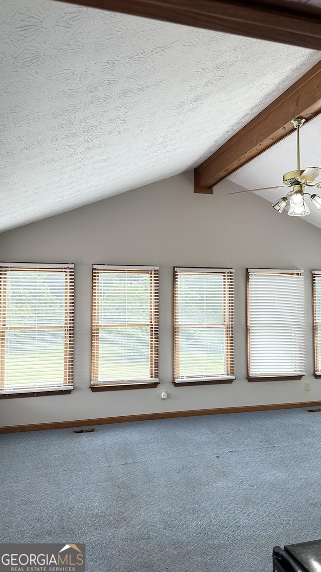 interior space featuring carpet floors, beamed ceiling, and a textured ceiling