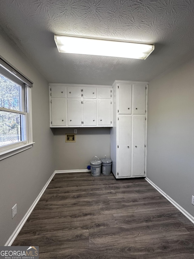 washroom with cabinet space, baseboards, washer hookup, and dark wood finished floors