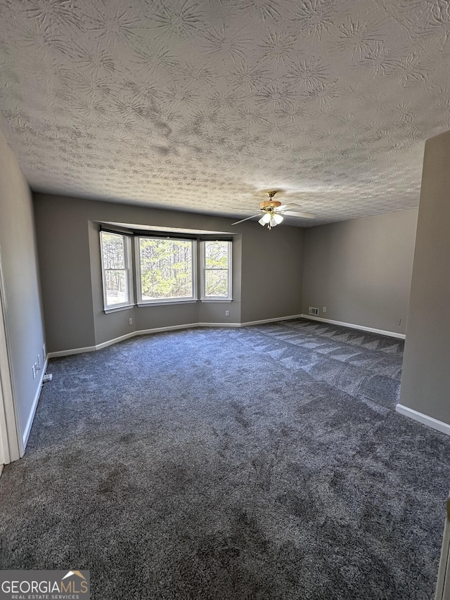 carpeted empty room with ceiling fan, a textured ceiling, and baseboards