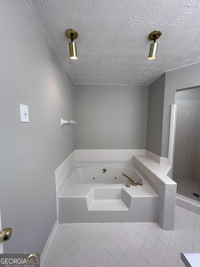 bathroom featuring a tub with jets, a tile shower, a textured ceiling, and tile patterned floors