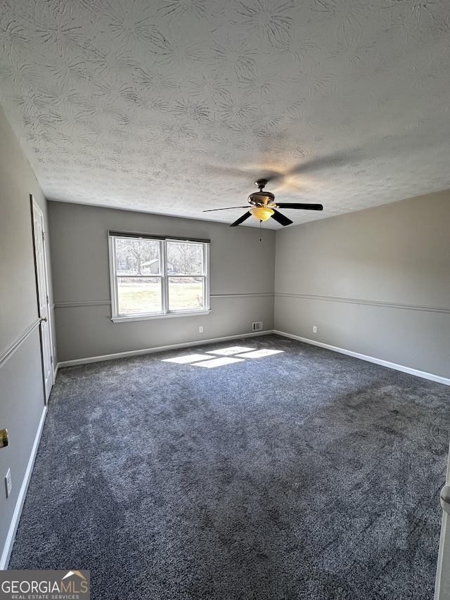 carpeted spare room with a textured ceiling, a ceiling fan, and baseboards