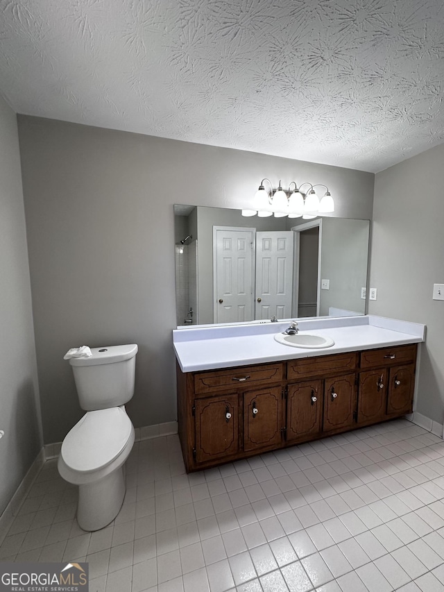 bathroom with a textured ceiling, tile patterned flooring, toilet, vanity, and baseboards