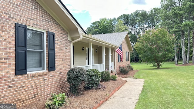 view of property exterior featuring covered porch, brick siding, and a yard