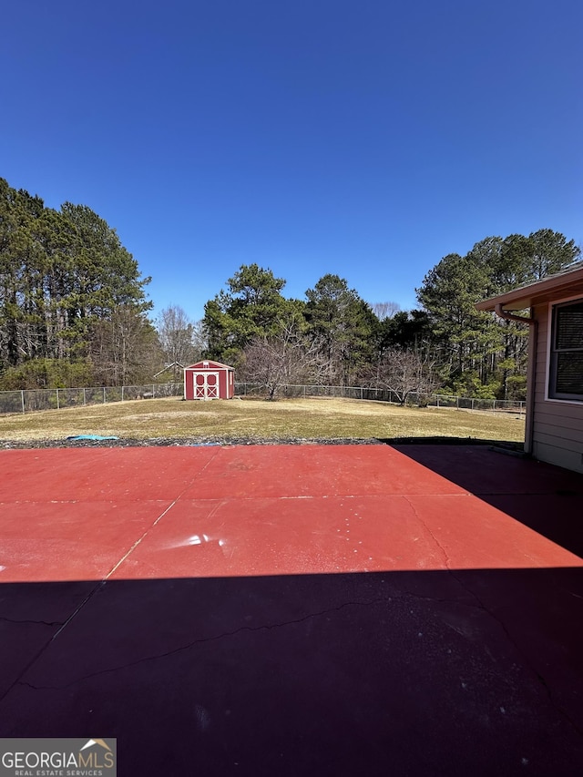 view of sport court featuring a shed and fence