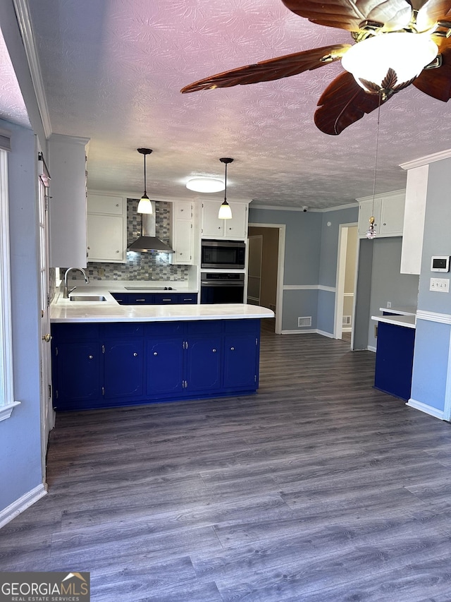 kitchen featuring blue cabinets, light countertops, visible vents, and wall chimney exhaust hood