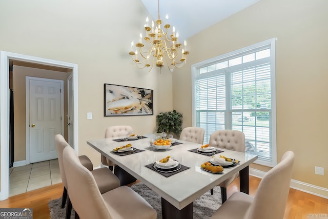 dining area with an inviting chandelier, lofted ceiling, and light wood-type flooring