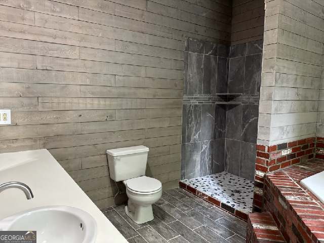 bathroom featuring toilet, sink, and a tile shower