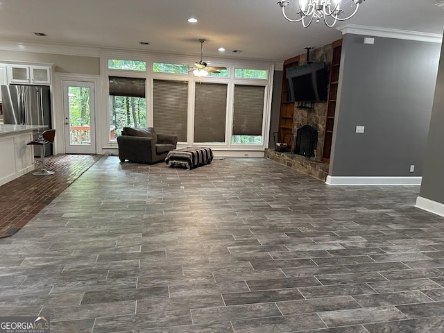 unfurnished living room featuring crown molding, a fireplace, and ceiling fan with notable chandelier