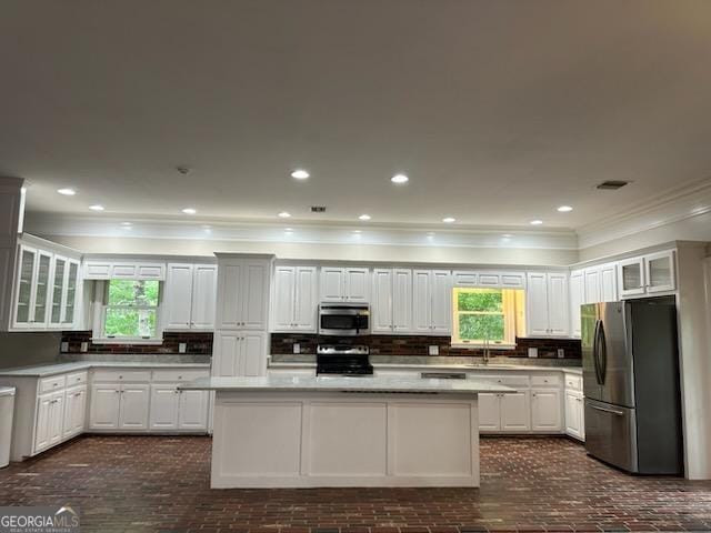 kitchen with stainless steel appliances, white cabinetry, a center island, and tasteful backsplash