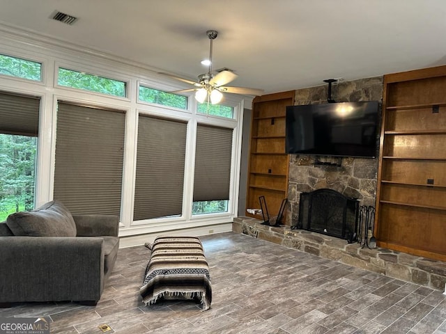 living room with ceiling fan, plenty of natural light, a fireplace, and built in shelves