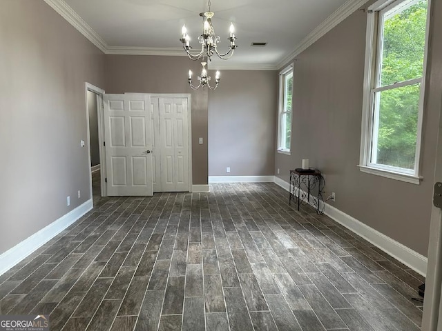 empty room with a notable chandelier, ornamental molding, and dark hardwood / wood-style floors