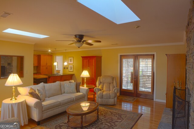 living room with a skylight, visible vents, crown molding, and light wood finished floors