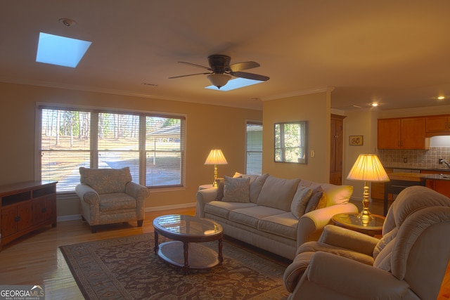 living area featuring light wood finished floors, plenty of natural light, and crown molding