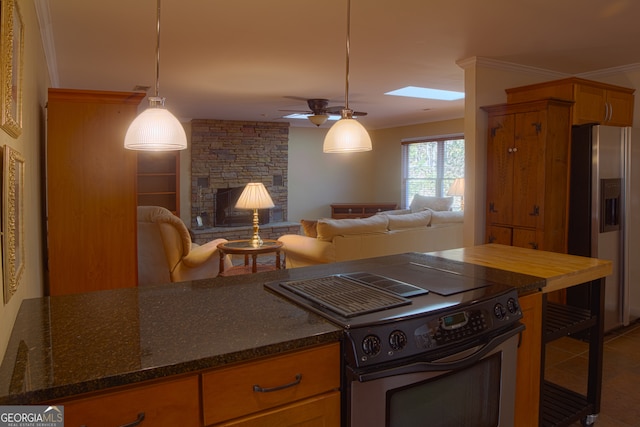 kitchen featuring open floor plan, stainless steel appliances, crown molding, and a stone fireplace