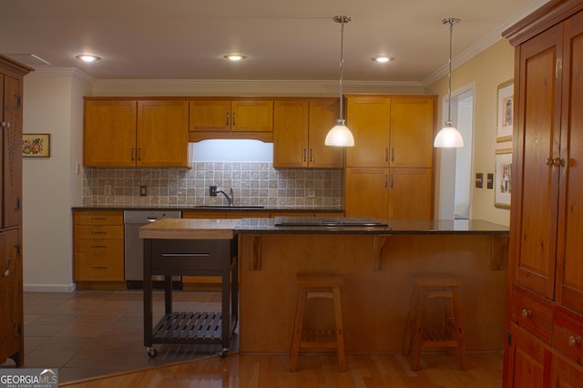 kitchen featuring dishwasher, dark countertops, a sink, and crown molding